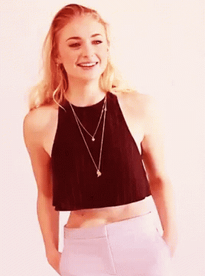 A Woman In A Black Crop Top And White Pants Smiles GIF