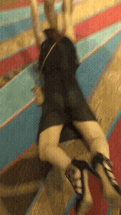 A Woman In A Black Dress And High Heels Is Laying On The Ground GIF
