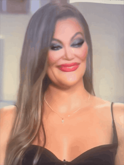 A Woman In A Black Dress Has A Cross Necklace GIF