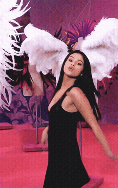 A Woman In A Black Dress Has White Feathered Wings On Her Head GIF