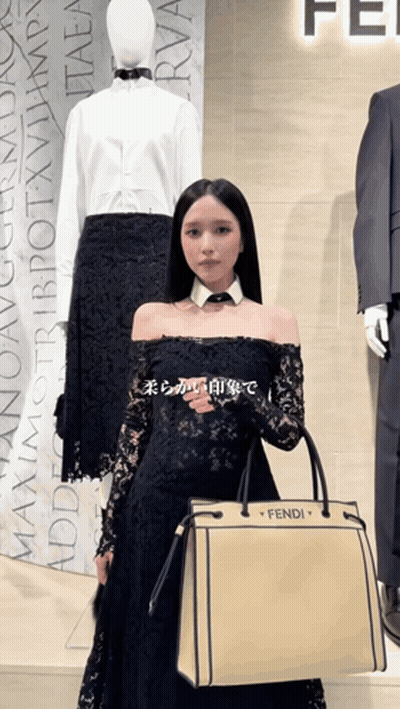 A Woman In A Black Dress Holding A Fendi Bag GIF