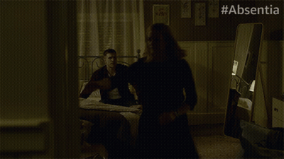 A Woman In A Black Dress Is Dancing In A Dark Room With #Absentia Written On The Bottom GIF