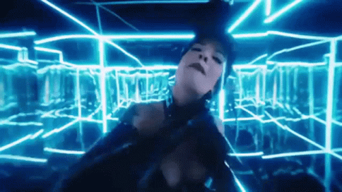 A Woman In A Black Dress Is Dancing In A Room With Blue Lights GIF