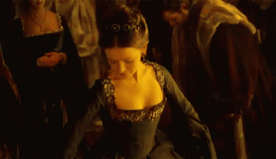 A Woman In A Black Dress Is Dancing In Front Of A Crowd Of People In A Dark Room . GIF