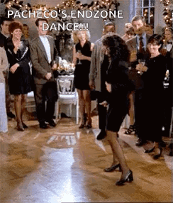 A Woman In A Black Dress Is Dancing On A Dance Floor In Front Of A Crowd Of People . GIF