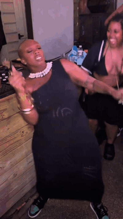 A Woman In A Black Dress Is Dancing With A Man In A Bikini GIF