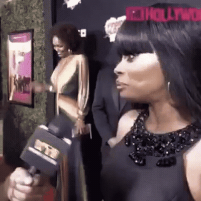 A Woman In A Black Dress Is Holding A Microphone In Her Hand . GIF