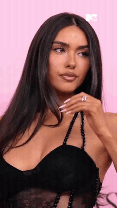 A Woman In A Black Dress Is Holding A Necklace And Wearing A Ring . GIF