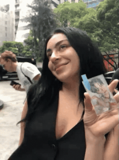 a woman in a black dress is holding a picture of a man in a white shirt