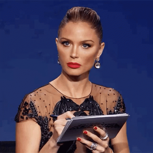 A Woman In A Black Dress Is Holding A Piece Of Paper In Her Hands . GIF