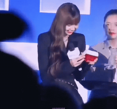 A Woman In A Black Dress Is Holding A Red Box In Her Hands . GIF