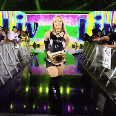 A Woman In A Black Dress Is Holding A Wrestling Championship GIF
