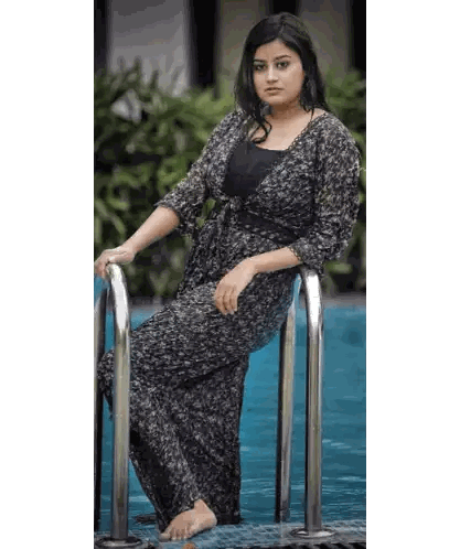 A Woman In A Black Dress Is Leaning On A Metal Railing Next To A Pool Sticker