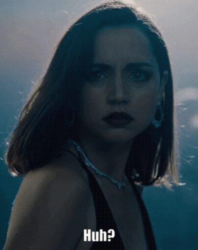 A Woman In A Black Dress Is Looking At The Camera With The Words Huh Below Her GIF