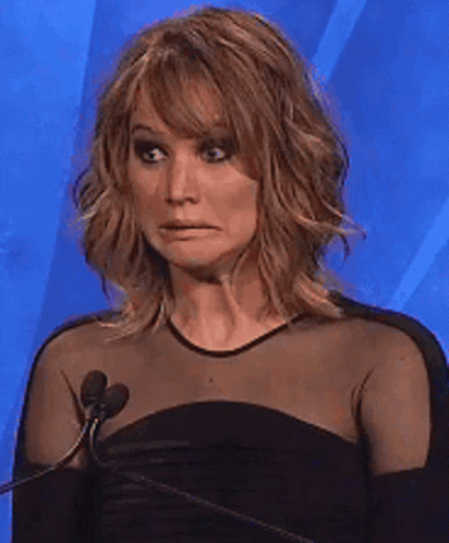A Woman In A Black Dress Is Making A Funny Face In Front Of Two Microphones GIF