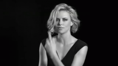 A Woman In A Black Dress Is Making A Gesture With Her Hand GIF