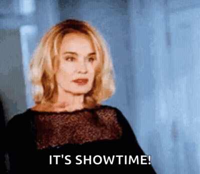 A Woman In A Black Dress Is Saying It 'S Showtime ! GIF