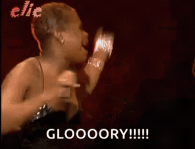 A Woman In A Black Dress Is Singing Into A Microphone And Says Gloooory . GIF