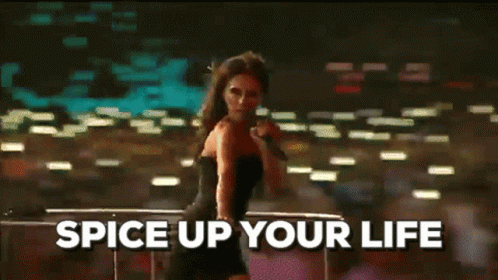 A Woman In A Black Dress Is Singing Into A Microphone With The Words Spice Up Your Life Above Her GIF