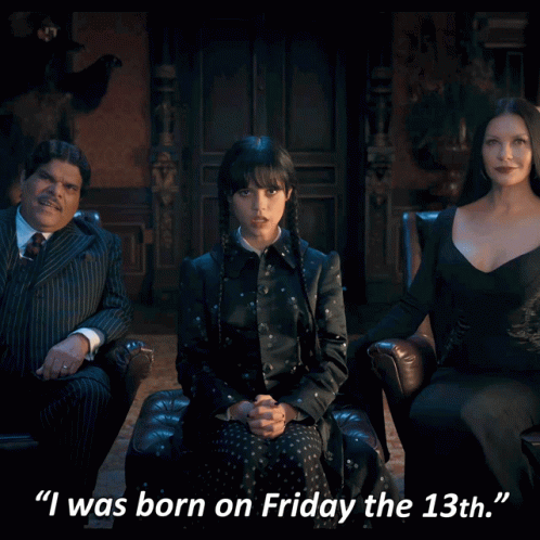 A Woman In A Black Dress Is Sitting In A Chair Next To A Man In A Suit And A Woman In A Dress GIF