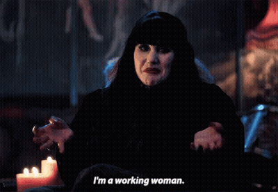 A Woman In A Black Dress Is Sitting In Front Of A Candle And Says I 'M A Working Woman . GIF