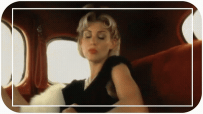 A Woman In A Black Dress Is Sitting In The Back Seat Of A Car With Her Eyes Closed GIF