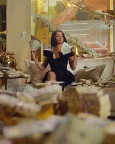 A Woman In A Black Dress Is Sitting On A Couch Holding Money GIF