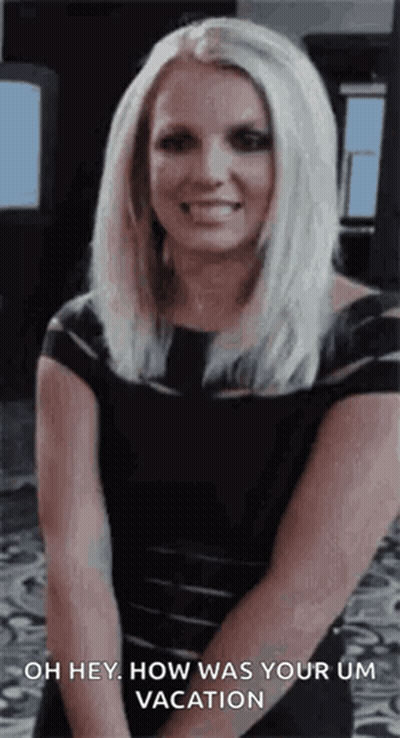 A Woman In A Black Dress Is Smiling And Saying Oh Hey How Was Your Um Vacation GIF