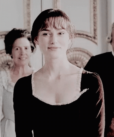 A Woman In A Black Dress Is Smiling While Standing Next To A Man And Woman . GIF