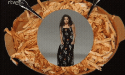 A Woman In A Black Dress Is Standing In A Bowl Of Shredded Meat GIF
