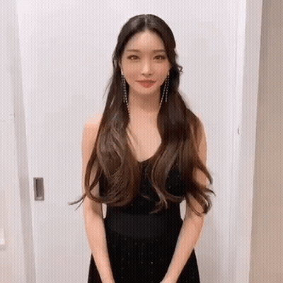 A Woman In A Black Dress Is Standing In Front Of A Door . GIF