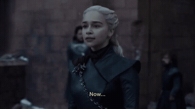 A Woman In A Black Dress Is Standing In Front Of A Large Crowd Of People . GIF