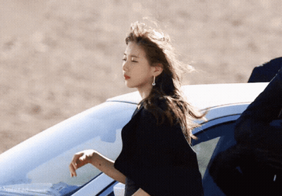 A Woman In A Black Dress Is Standing Next To A Car GIF