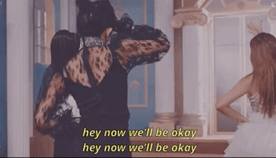 A Woman In A Black Dress Is Standing Next To Another Woman In A White Dress In Front Of A Mirror . GIF