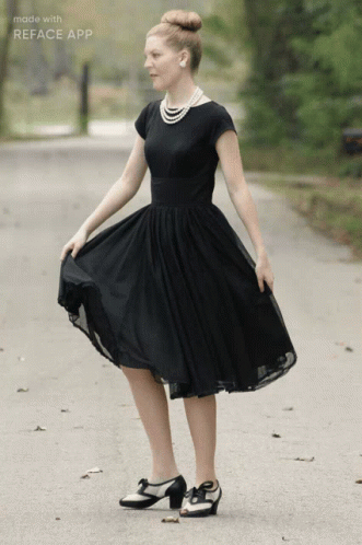 A Woman In A Black Dress Is Standing On A Road With The Words Made With Reface App Above Her GIF