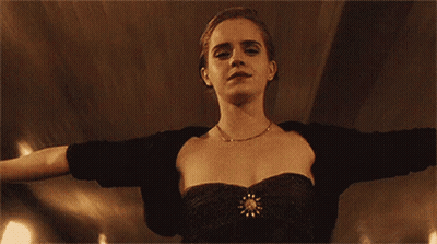 A Woman In A Black Dress Is Standing With Her Arms Outstretched And Looking At The Camera . GIF