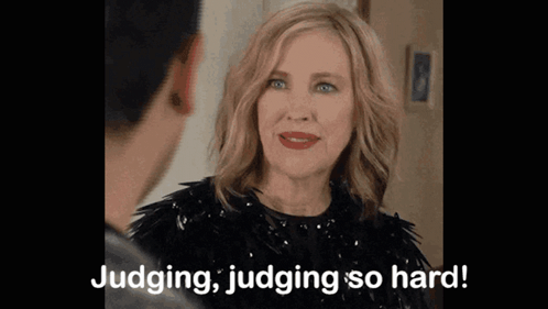 A Woman In A Black Dress Is Talking To A Man And Saying Judging , Judging So Hard . GIF
