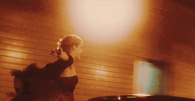 A Woman In A Black Dress Is Walking In Front Of A Building GIF
