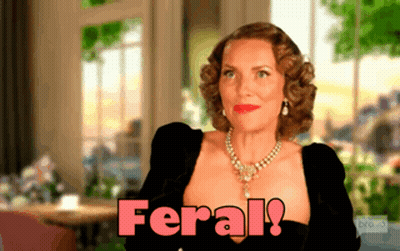 A Woman In A Black Dress Says Feral In Pink Letters GIF