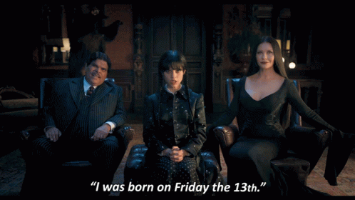 A Woman In A Black Dress Says " I Was Born On Friday The 13Th " Next To A Man In A Suit GIF