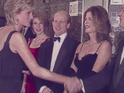 A Woman In A Black Dress Shakes Hands With A Man In A Tuxedo GIF