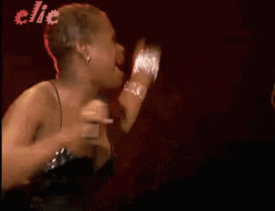 A Woman In A Black Dress Singing Into A Microphone With The Word Clic In The Background GIF