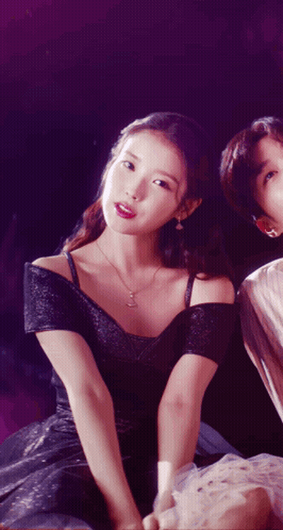 A Woman In A Black Dress Sitting Next To A Man In A White Shirt GIF