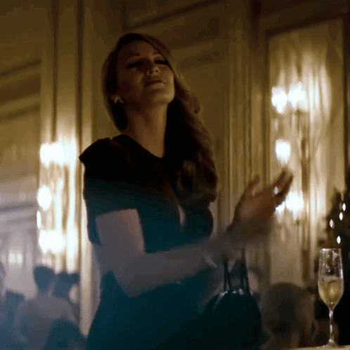 A Woman In A Black Dress Stands In A Dark Room GIF