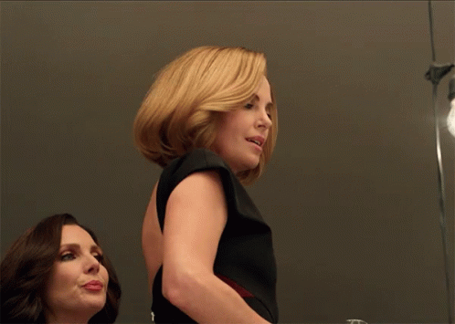 A Woman In A Black Dress Stands Next To Another Woman In A Red Dress GIF