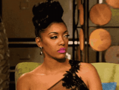 A Woman In A Black Dress With Pink Lipstick Is Sitting On A Chair . GIF