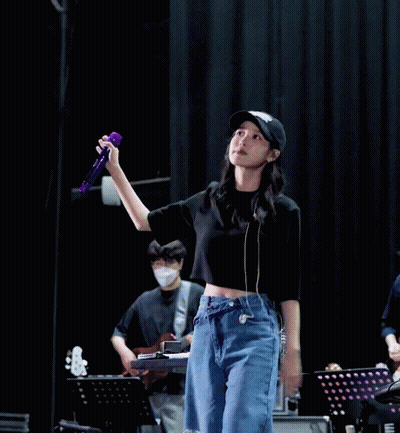 A Woman In A Black Hat Holds A Purple Microphone GIF