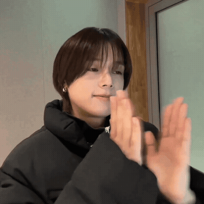 A Woman In A Black Jacket Is Clapping Her Hands Together GIF