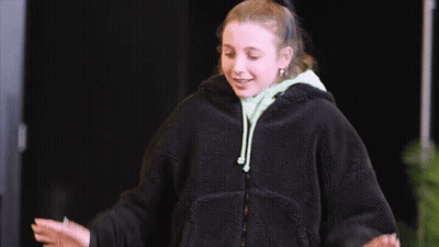 A Woman In A Black Jacket Is Giving A Thumbs Up Sign GIF