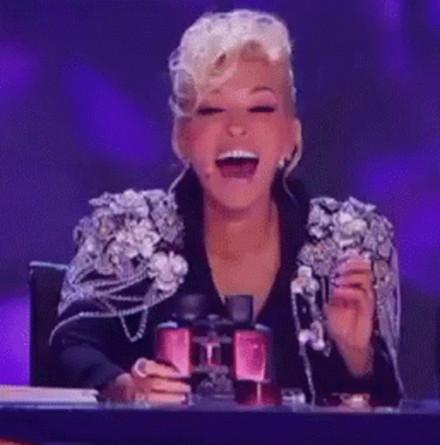 A Woman In A Black Jacket Is Laughing And Holding A Pair Of Binoculars GIF